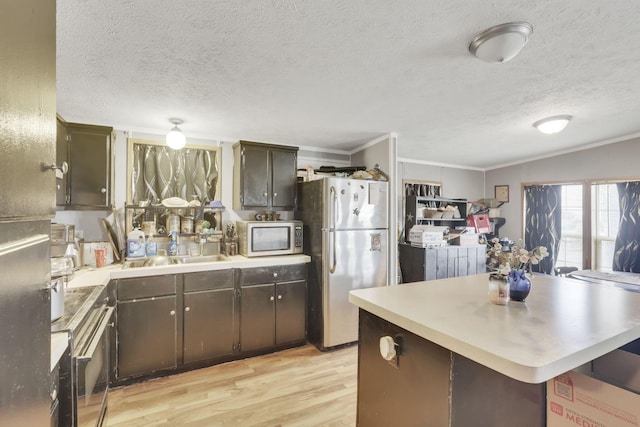 kitchen featuring crown molding, appliances with stainless steel finishes, light countertops, a sink, and light wood finished floors