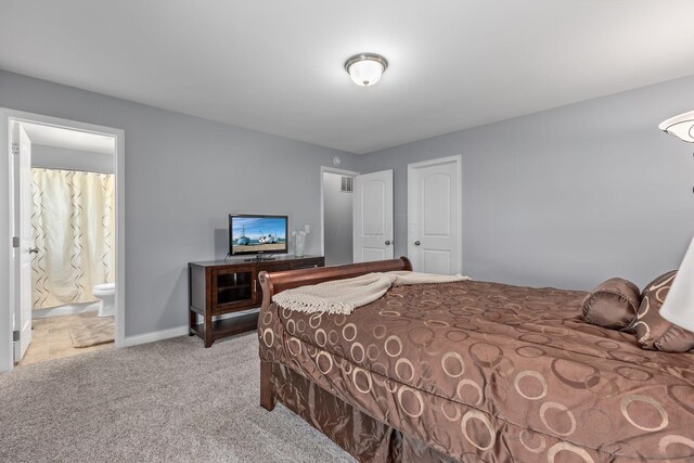 carpeted bedroom with ensuite bath and baseboards