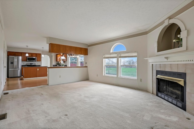 unfurnished living room featuring crown molding, a textured ceiling, light colored carpet, and a fireplace