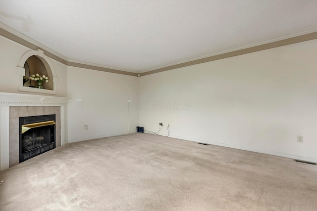 unfurnished living room featuring crown molding, a tile fireplace, carpet flooring, and visible vents