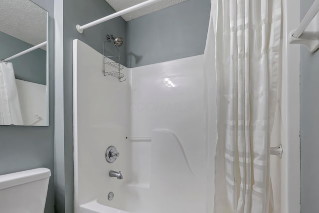 full bath with shower / bath combination with curtain, a textured ceiling, and toilet