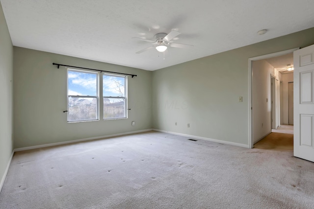empty room featuring light carpet, baseboards, a ceiling fan, and visible vents