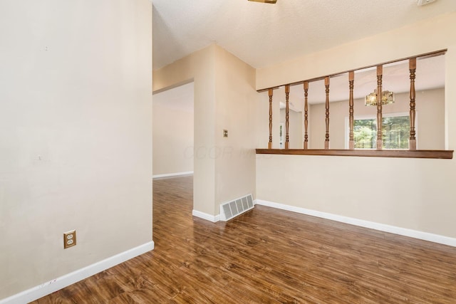 unfurnished room featuring baseboards, a textured ceiling, wood finished floors, and visible vents