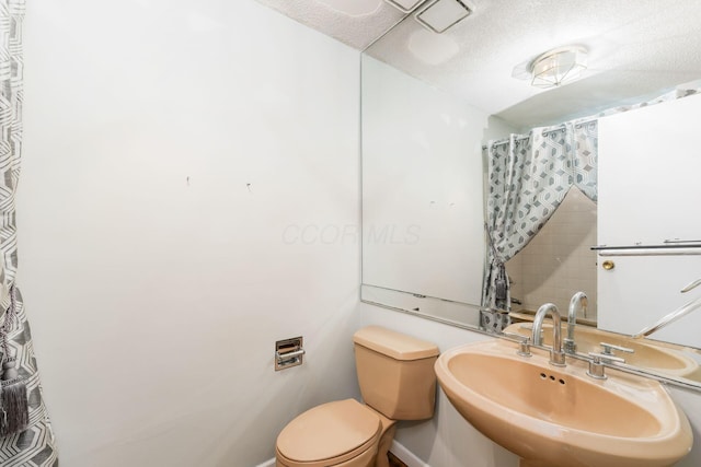 full bath featuring toilet, a textured ceiling, and a sink