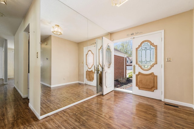 foyer with baseboards, wood finished floors, and visible vents