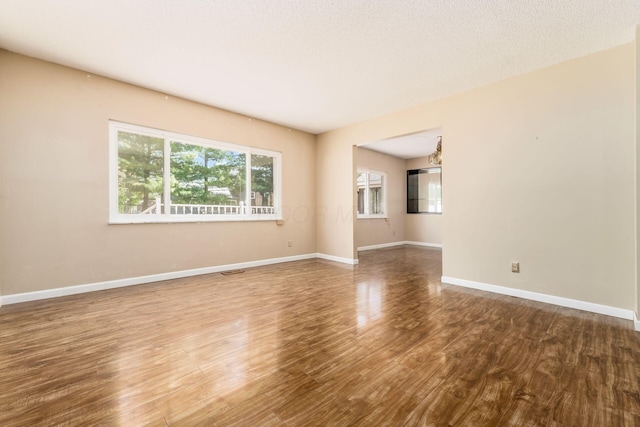 spare room with baseboards, wood finished floors, and visible vents