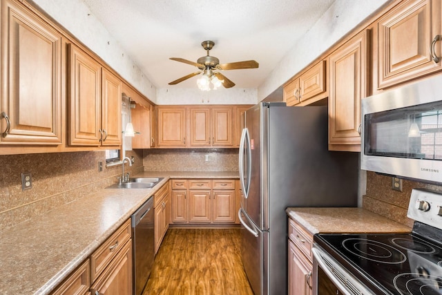 kitchen with ceiling fan, dark wood-style flooring, tasteful backsplash, a sink, and stainless steel appliances