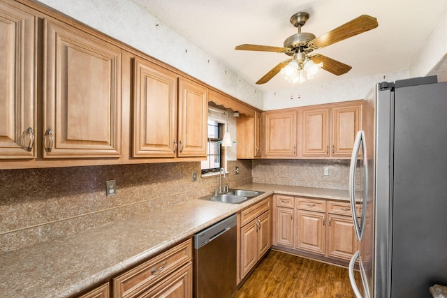 kitchen featuring appliances with stainless steel finishes, a sink, dark wood finished floors, a ceiling fan, and tasteful backsplash