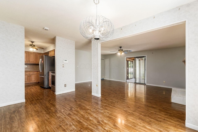 unfurnished living room featuring dark wood-style flooring, baseboards, and ceiling fan with notable chandelier