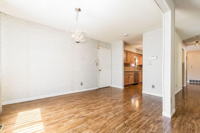 unfurnished living room featuring visible vents, baseboards, wood finished floors, and an inviting chandelier