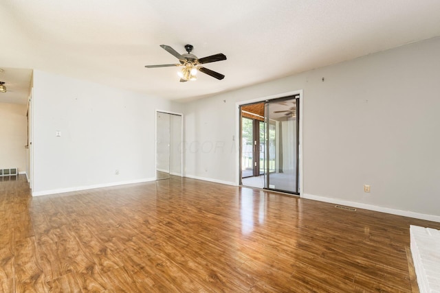spare room with baseboards, a ceiling fan, wood finished floors, and visible vents