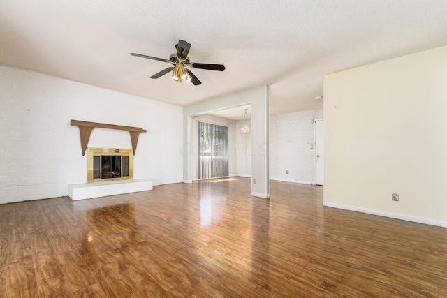 unfurnished living room featuring baseboards, a glass covered fireplace, ceiling fan, and wood finished floors
