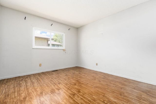unfurnished room featuring light wood-style floors, baseboards, and visible vents