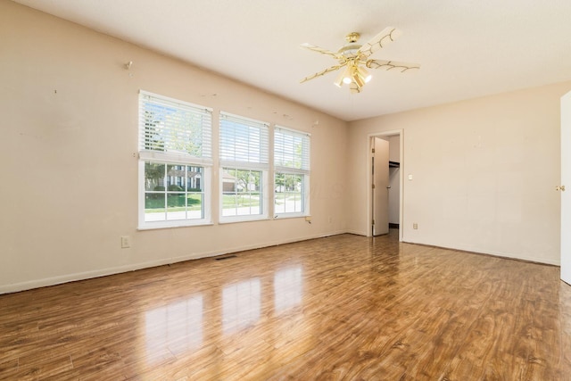 spare room featuring baseboards, wood finished floors, and visible vents