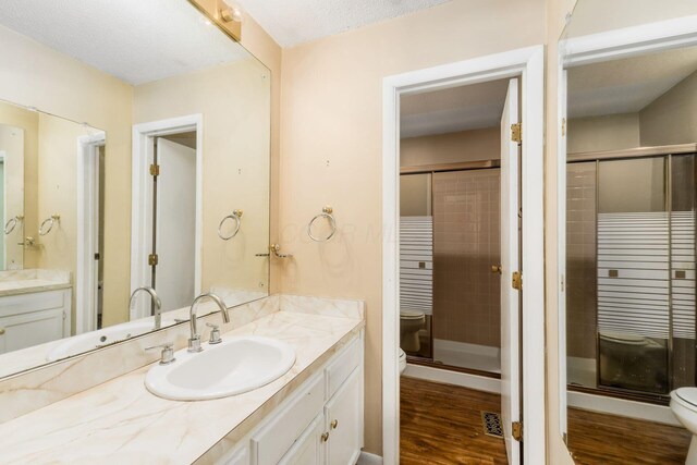 full bath featuring vanity, a shower stall, toilet, and wood finished floors