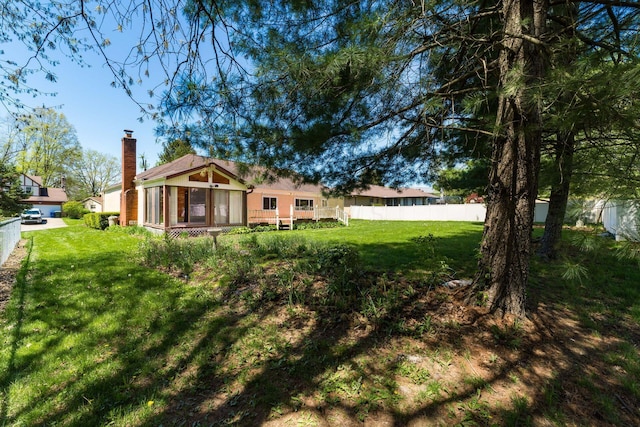 exterior space featuring fence, a chimney, a front lawn, and a deck