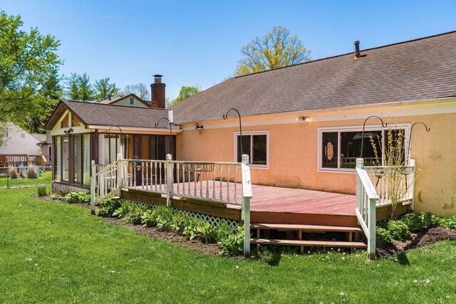rear view of house with a lawn, a shingled roof, a sunroom, and a chimney
