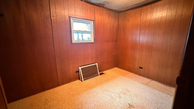 unfurnished room with carpet floors, wood walls, and visible vents