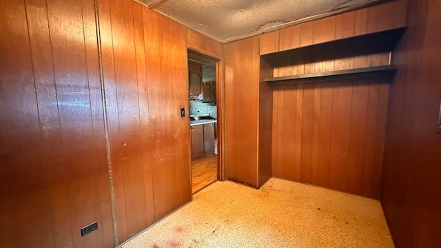 corridor with a textured ceiling and wood walls