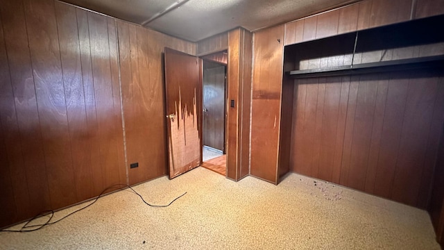 unfurnished bedroom with wood walls and a closet