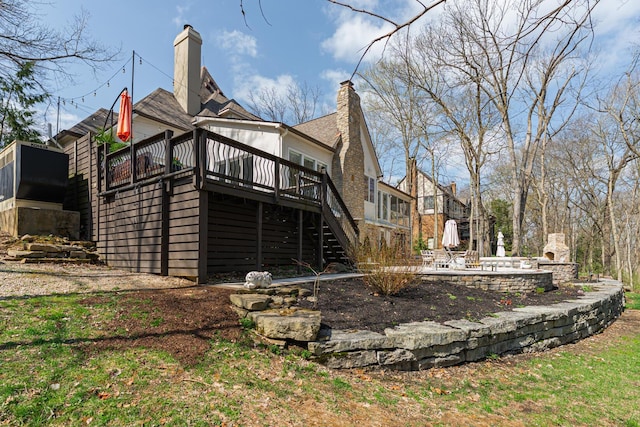 rear view of house featuring a chimney, stairway, a deck, and a patio area