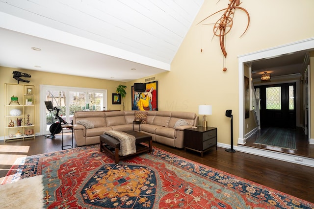 living room with high vaulted ceiling, dark wood-type flooring, baseboards, and visible vents