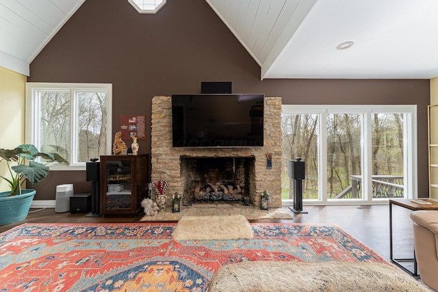 living room with a stone fireplace, lofted ceiling, and wood finished floors