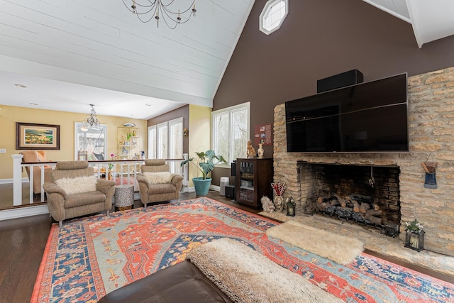 living room featuring high vaulted ceiling, baseboards, wood finished floors, a stone fireplace, and an inviting chandelier