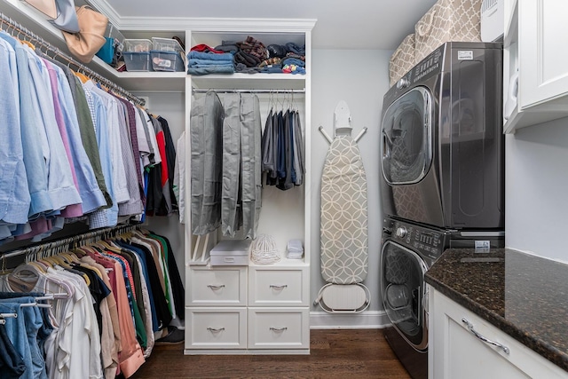 clothes washing area with stacked washer and dryer, dark wood-style flooring, and cabinet space