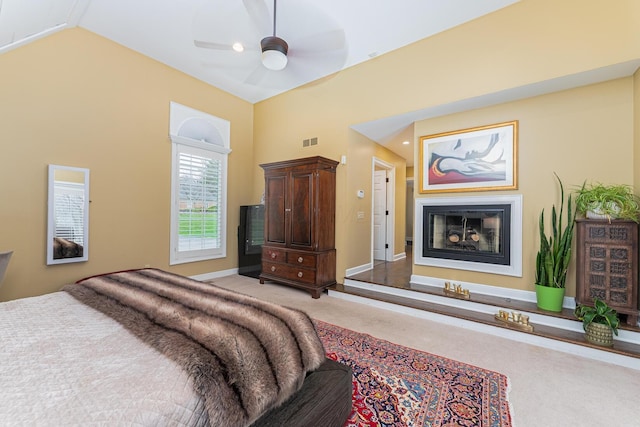 bedroom with visible vents, baseboards, ceiling fan, a glass covered fireplace, and light colored carpet