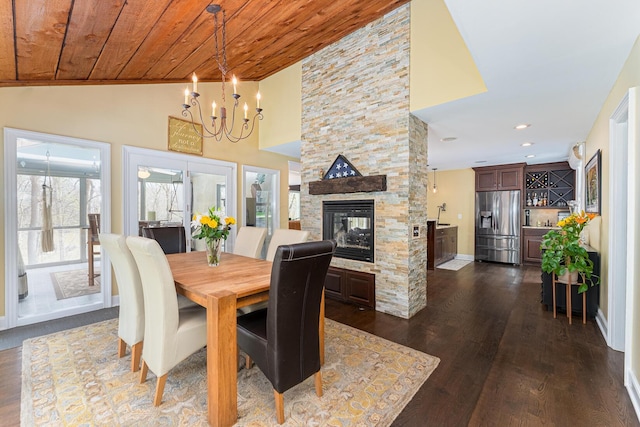 dining area featuring an inviting chandelier, wood ceiling, a stone fireplace, and dark wood-type flooring
