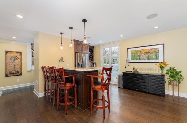 bar featuring dark wood finished floors, stainless steel fridge with ice dispenser, indoor wet bar, and baseboards