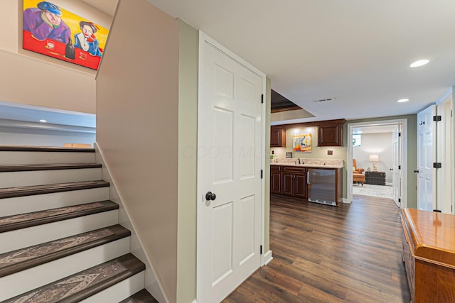stairway with visible vents, baseboards, wood finished floors, bar area, and recessed lighting