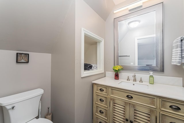 half bathroom featuring toilet, vanity, and vaulted ceiling