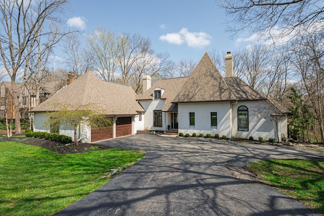 view of front of property with a front lawn, driveway, stucco siding, and a chimney