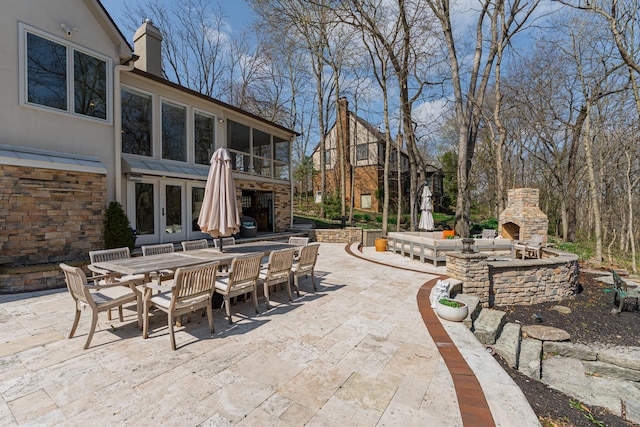 view of patio / terrace featuring an outdoor stone fireplace, outdoor dining area, and french doors