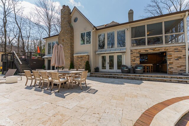 rear view of property featuring french doors, a chimney, stucco siding, a patio, and outdoor dining area