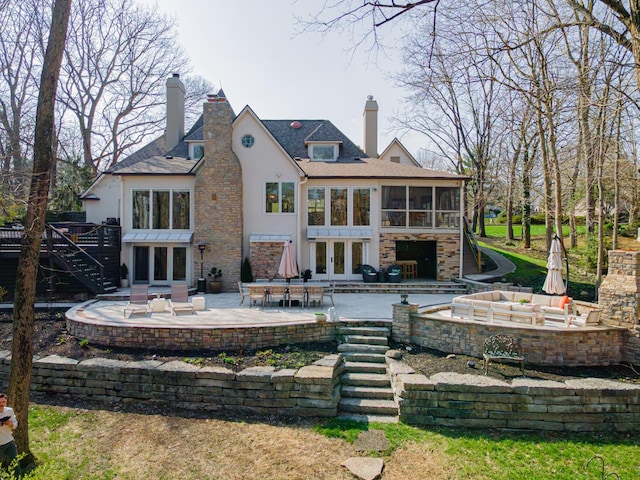 rear view of property featuring stairs, french doors, stucco siding, a sunroom, and a patio