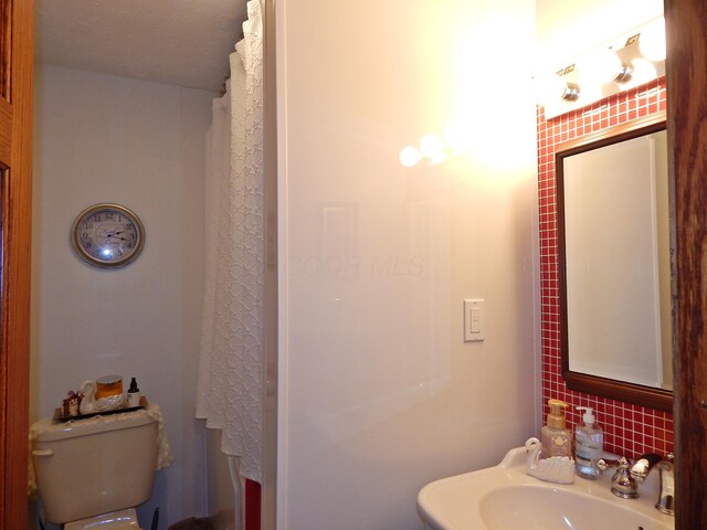 3061 County Road 11, Bellefontaine, OH 43311 - bathroom featuring a sink, toilet, decorative backsplash, and a shower with shower curtain