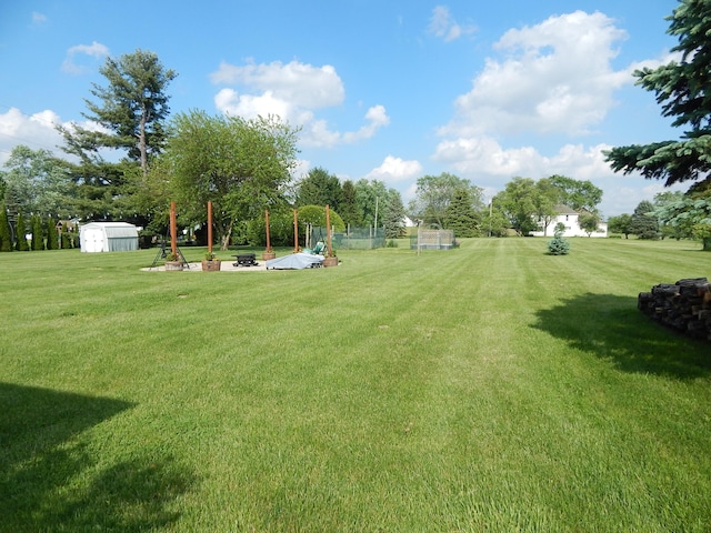 3061 County Road 11, Bellefontaine, OH 43311 - view of green lawn featuring a fire pit, a storage unit, and an outbuilding
