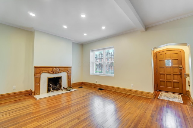 unfurnished living room with crown molding, wood-type flooring, a high end fireplace, baseboards, and visible vents