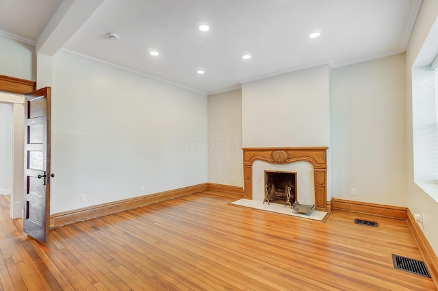unfurnished living room featuring visible vents, a premium fireplace, crown molding, baseboards, and light wood-style floors