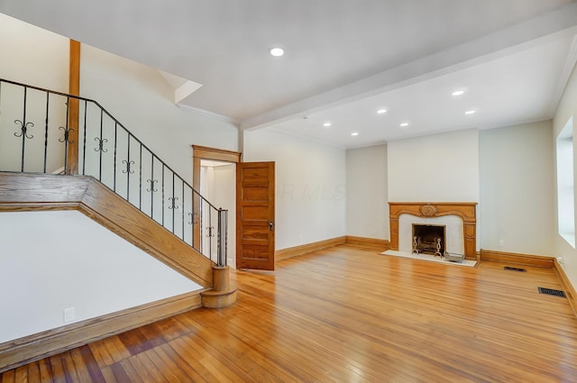 unfurnished living room with hardwood / wood-style flooring, baseboards, stairway, and visible vents