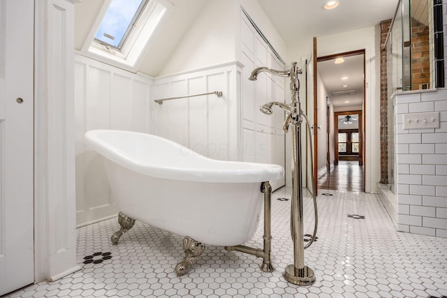 160 E Moler St, Columbus, OH 43207 - bathroom with a decorative wall, a freestanding tub, a skylight, tile patterned floors, and wainscoting
