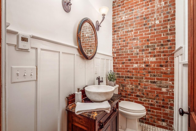 160 E Moler St, Columbus, OH 43207 - bathroom featuring a decorative wall, brick wall, vanity, wainscoting, and toilet