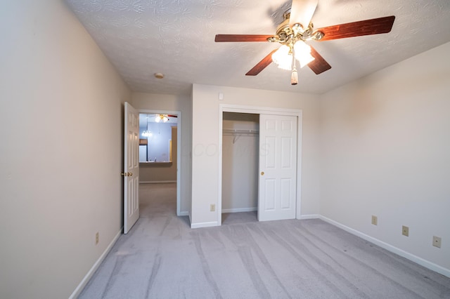 unfurnished bedroom featuring baseboards, a textured ceiling, a ceiling fan, light carpet, and a closet