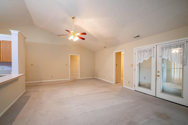 unfurnished living room featuring a ceiling fan, light carpet, lofted ceiling, and visible vents