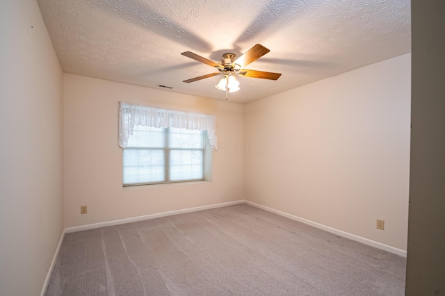 empty room featuring baseboards, a textured ceiling, visible vents, a ceiling fan, and light carpet