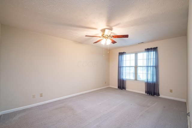 empty room featuring a textured ceiling, baseboards, light colored carpet, and ceiling fan