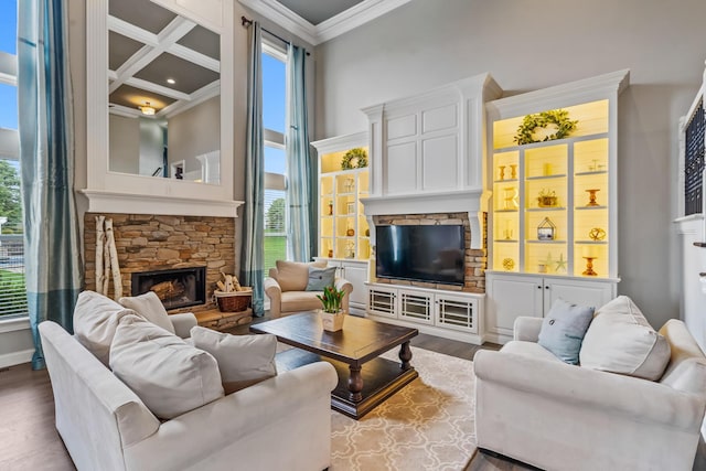 living room with coffered ceiling, crown molding, dark wood-style flooring, a high ceiling, and a fireplace